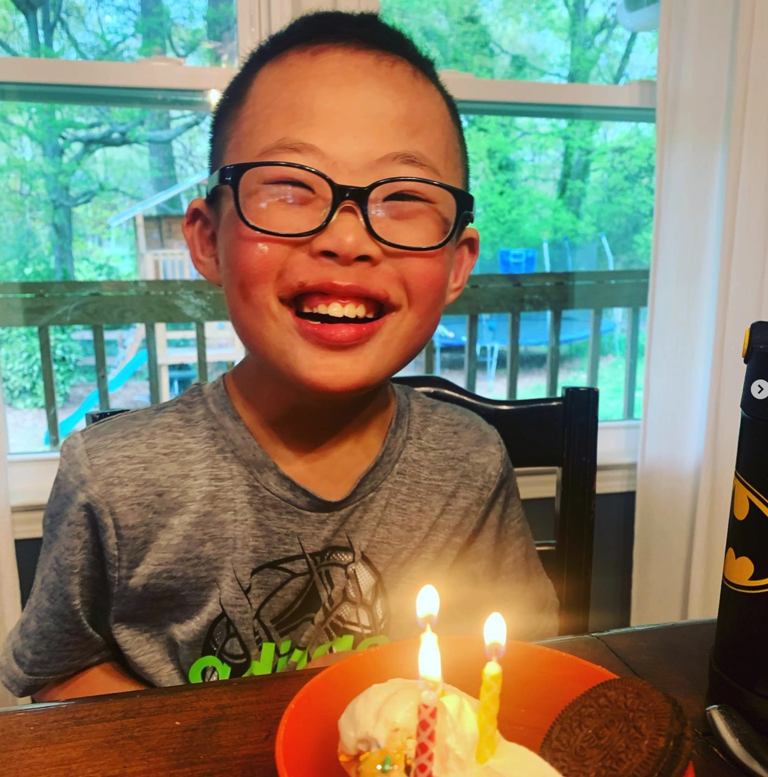 Kai, all smiles at the table over a birthday treat with candles