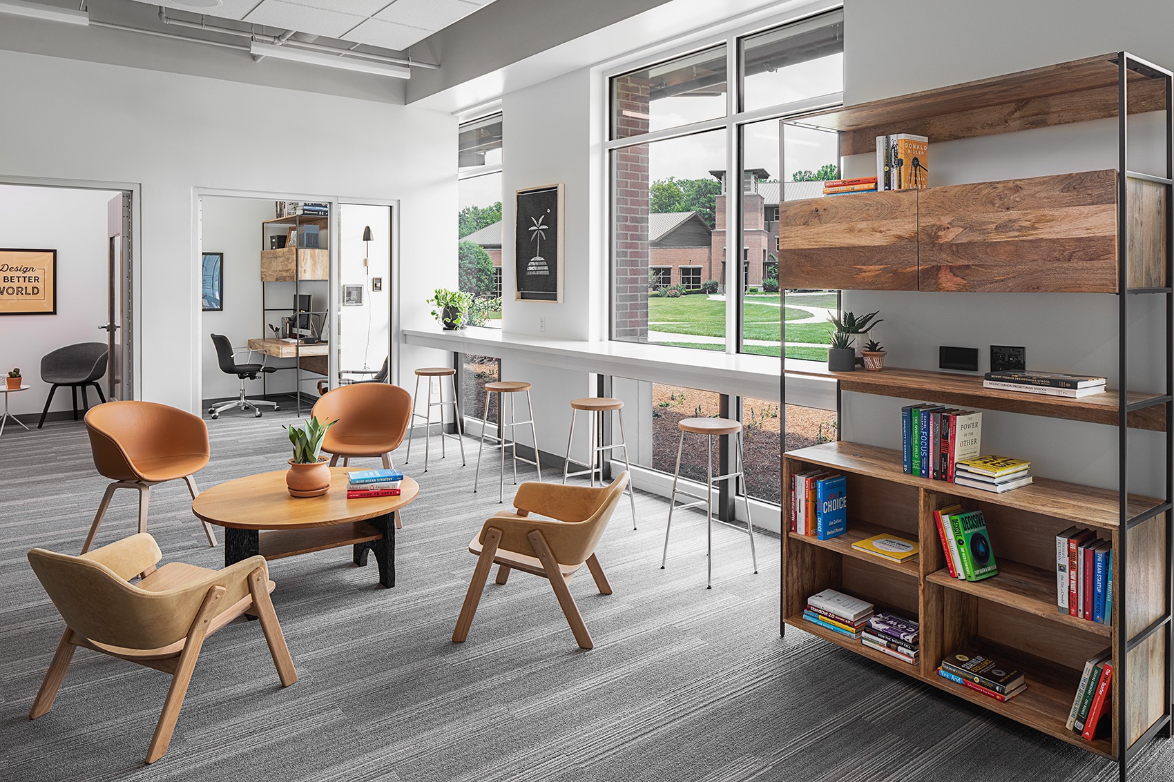 Collaborative lounge with modern seating, bookshelves, and Design a Better World signage
